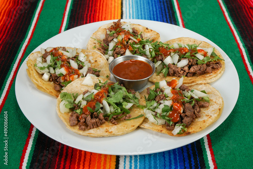 A delicious plate of carne asada tacos and a cup of salsa. photo