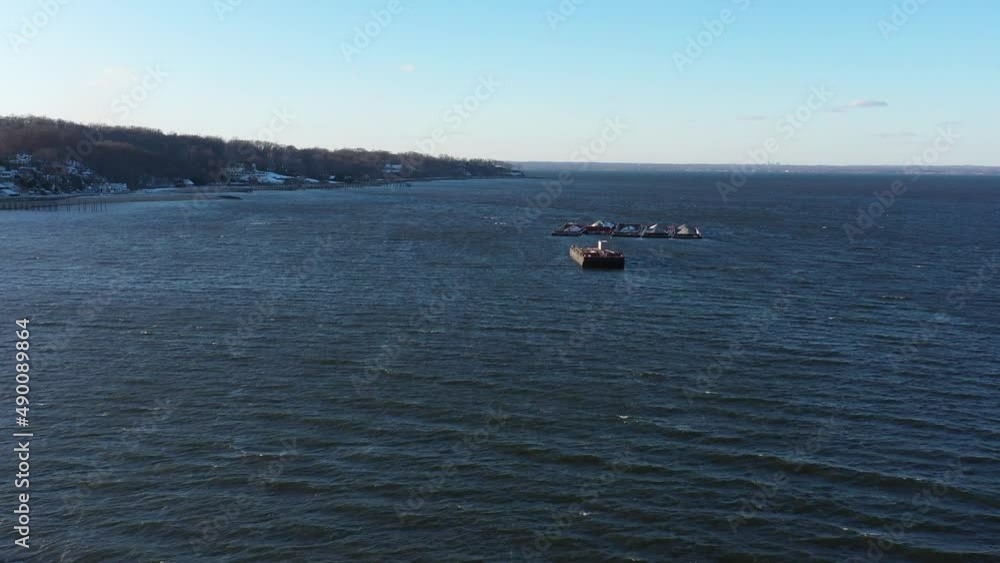 An aerial view of Hempstead Bay during a cold winter day. The camera dolly out over the water, flying over an empty barge anchored in the middle of the bay. There are other barges in the distance. An aerial view of Hempstead Bay during a cold winter day. The camera dolly out over the water, flying over an empty barge anchored in the middle of the bay. There are other barges in the distance.