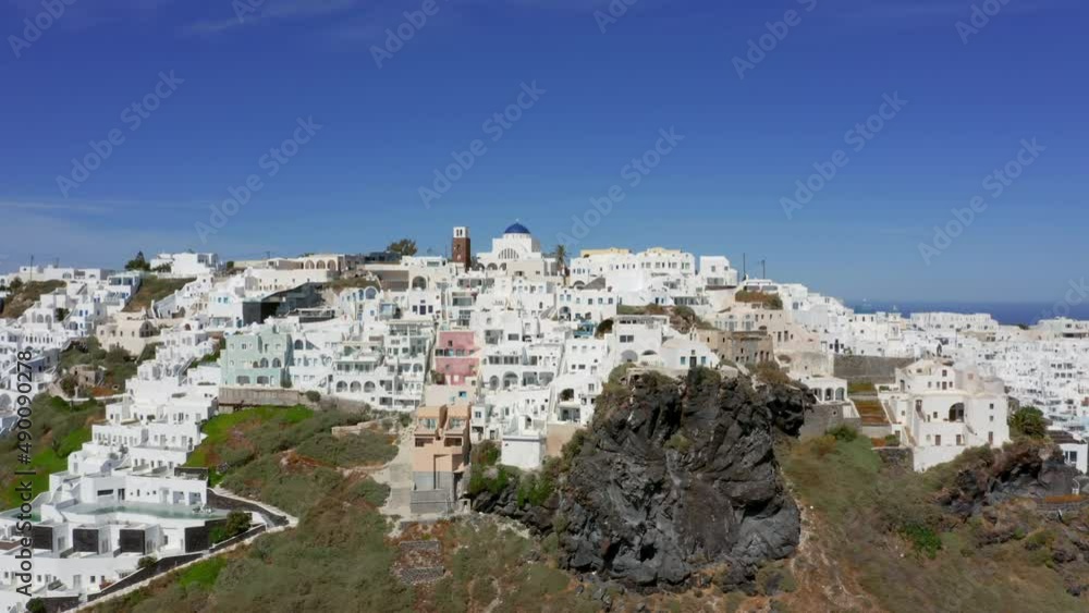 Slow panning drone shot of Fira in Santorini, Greece on a sunny day Slow panning drone shot of Fira in Santorini, Greece on a sunny day