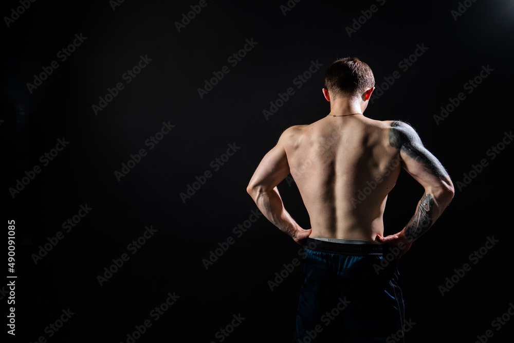 Man on black background keeps dumbbells pumped up in fitness active chest athlete muscular strong athletic hand, male pectoral. handsome power, gym fit back of the arm muscles Man on black background keeps dumbbells pumped up in fitness active chest athlete muscular strong athletic hand, male pectoral. handsome power, gym fit back of the arm muscles