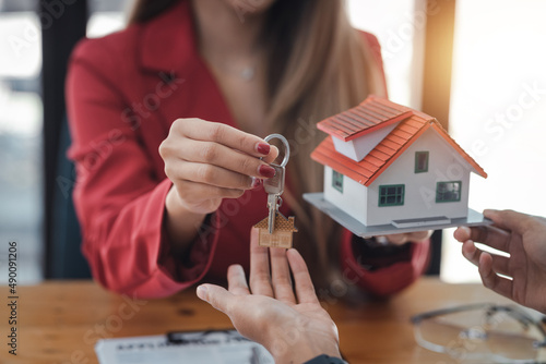 Real estate agent giving house key to the client after signing the real estate contract. Home and real estate trading concept. photo