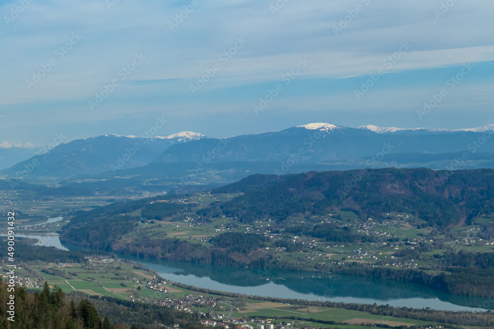 Scenic view on the Drava river in the Rosental valley on the way to Sinacher Gupf in Carinthia, Austria. Forest in early spring. The Hohe Tauern mountain range can be seen in the back. Sunny day. Hike