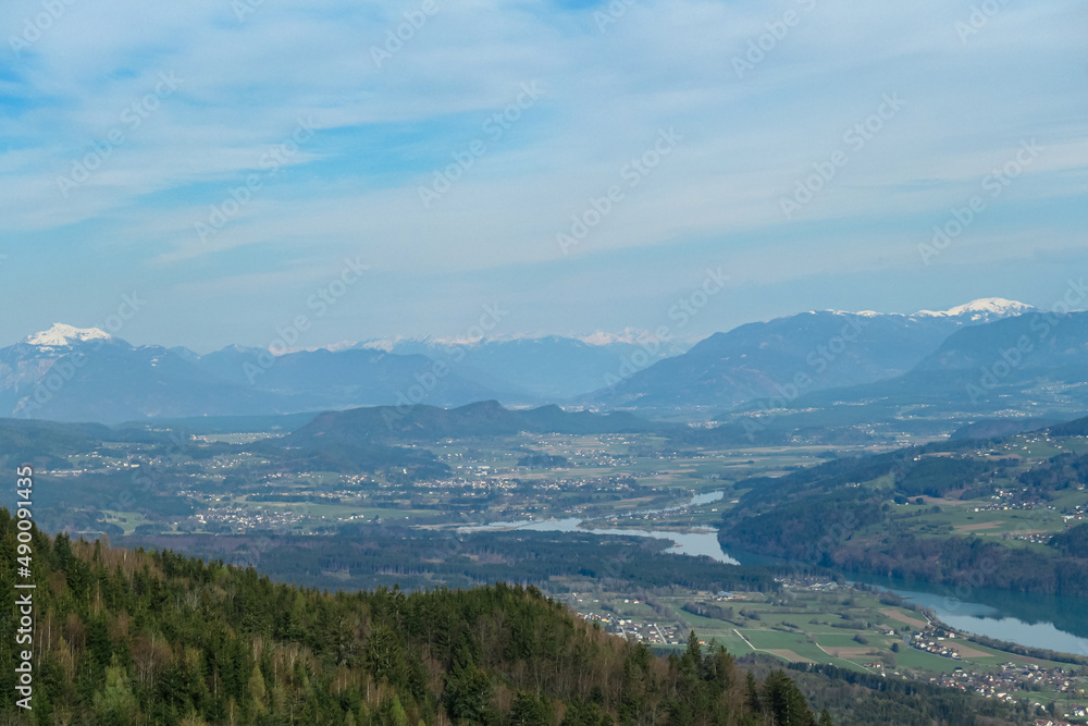 Scenic view on the Drava river in the Rosental valley on the way to Sinacher Gupf in Carinthia, Austria. Forest in early spring. The Hohe Tauern mountain range can be seen in the back. Sunny day. Hike