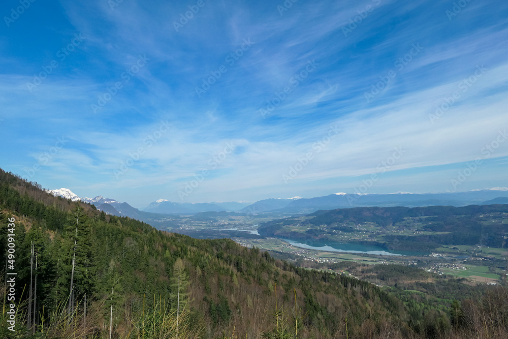 Scenic view on the Drava river in the Rosental valley on the way to Sinacher Gupf in Carinthia, Austria. Forest in early spring. The Hohe Tauern mountain range can be seen in the back. Sunny day. Hike