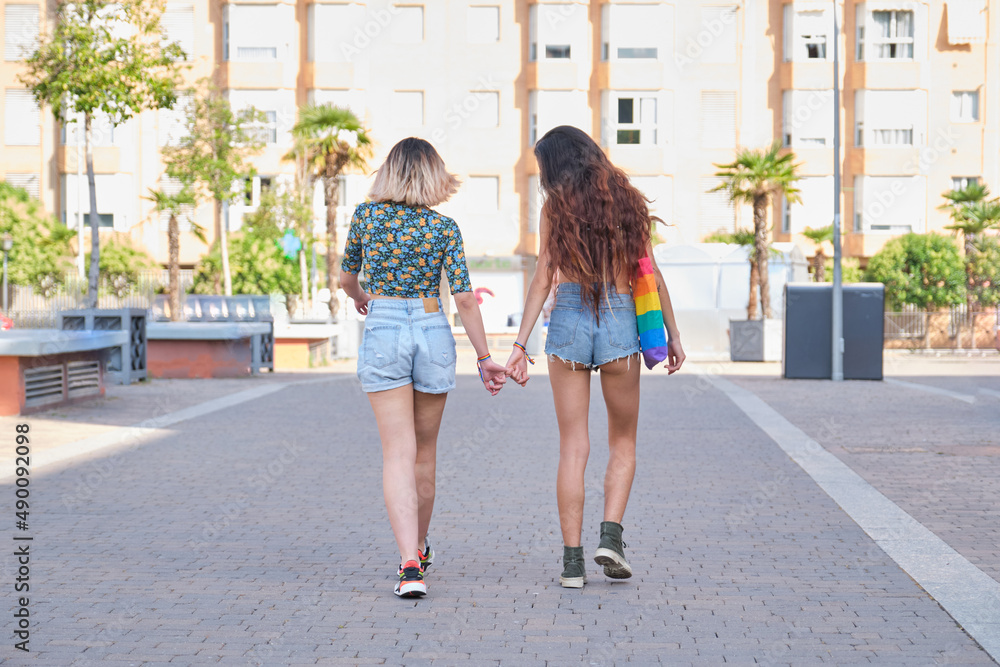 Young lesbian couple holding hands and walking backwards. LGBT relationship.