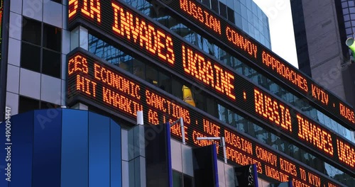A digital news stock market ticker reports Russia invades Ukraine.