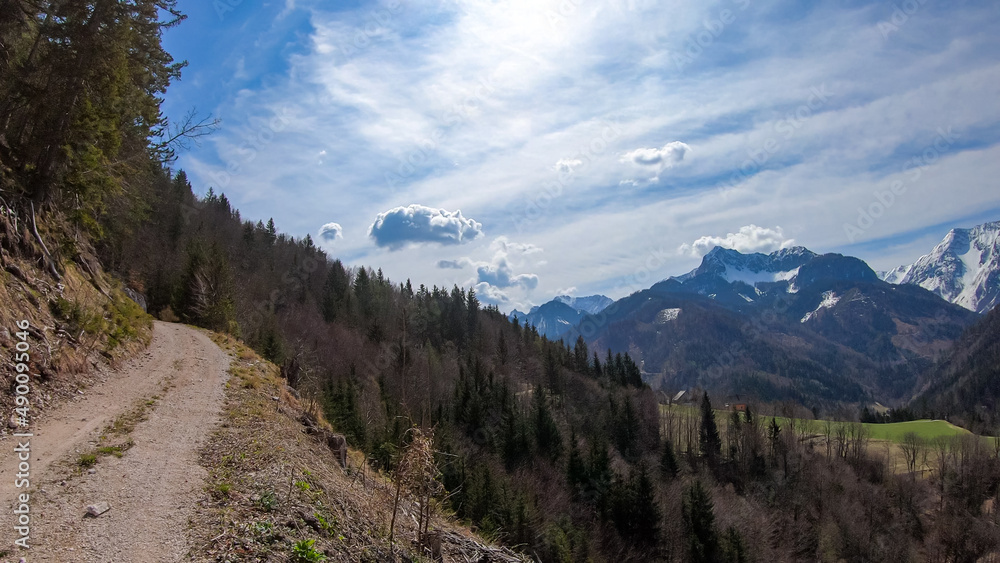 Scenic view of a hiking trail leading to the snow capped mountain peaks of Karawanks near Sinacher Gupf in Carinthia, Austria. Mount Wertatscha and Hochstuhl (Stol) is visible in early spring.Rosental