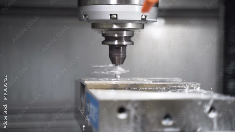 CNC machine drilling a hole in a metal plate, leaving metal splinters. CNC machine drilling a hole in a metal plate, leaving metal splinters.