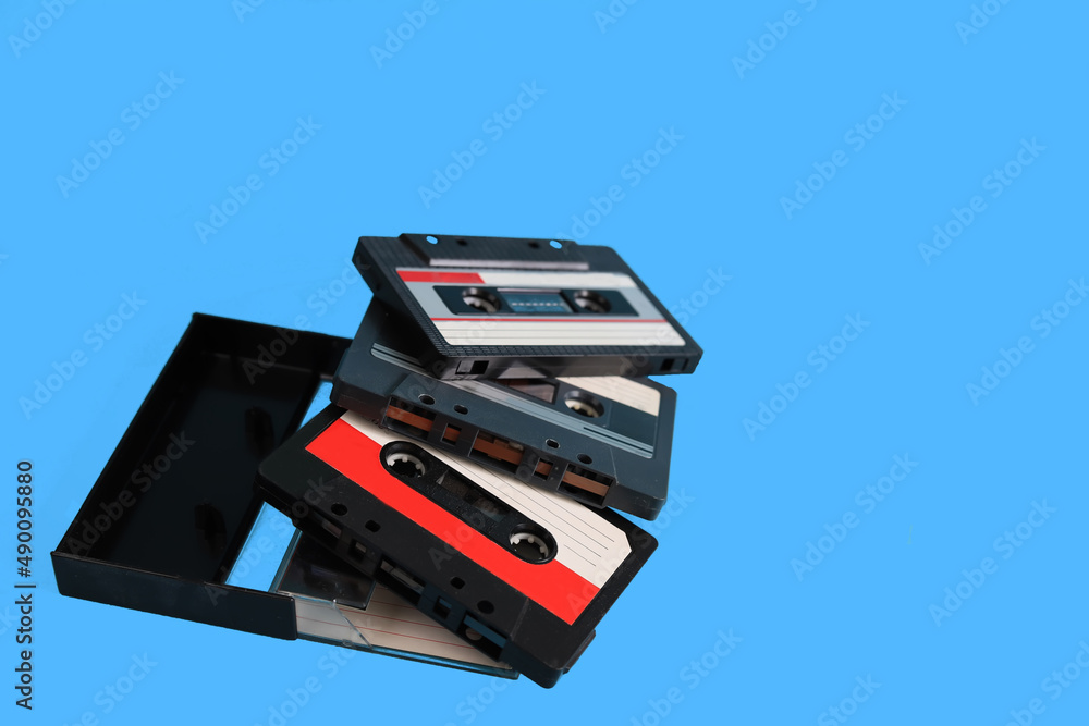 Pop music style attributes eighties, retro old school concept. Audio cassette on a bright blue creative background. Pop music style attributes eighties, retro old school concept. Audio cassette on a bright blue creative background.