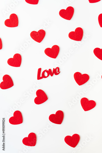 The background which consists of red hearts, the inscription love in the middle of the hearts. Vertical photo. Love concept, greeting card for valentine's day.