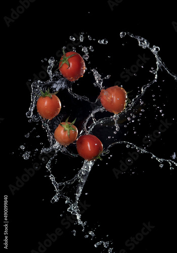 Fresh red Tomatoes in splash of water Isolated on black background