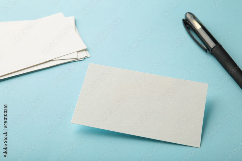 Blank white business cards with pen on blue paper background. Mockup for branding identity. Template for graphic designers portfolios. Blank white business cards with pen on blue paper background. Mockup for branding identity. Template for graphic designers portfolios.