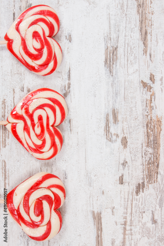 Sweet lollipop in shape of heart on rustic board. Surprise for birthday, valentine or different occasions. Place for text Sweet lollipop in shape of heart on rustic board. Surprise for birthday, valentine or different occasions. Place for text
