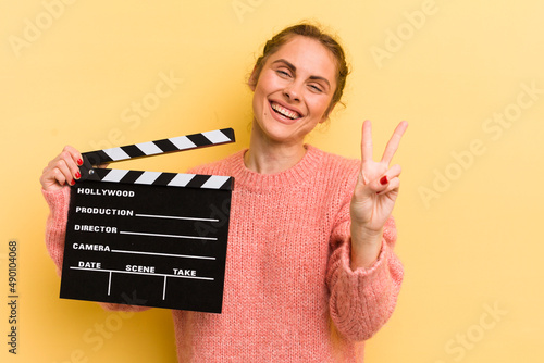 young pretty woman smiling and looking friendly, showing number two. cinema clapper concept photo