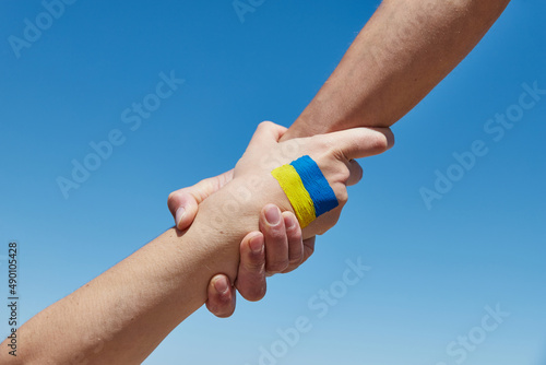 Lend a hand help painted in ukrainian flag colors against blue sky. Stand with Ukraine photo