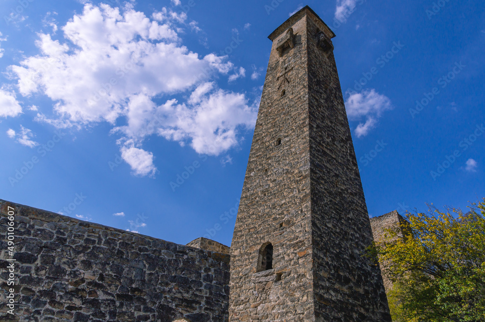 An ancient stone tower with a religious symbol in the form of a man. An ancient fortress structure for protection from attacks. An old medieval tower for monitoring enemies.