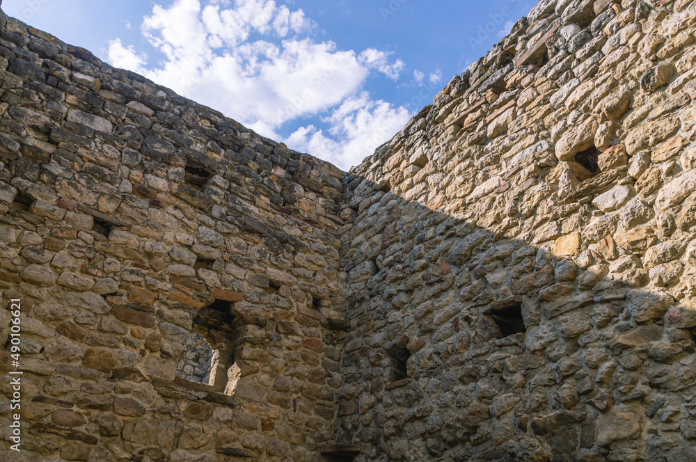 The wall of an ancient tower built of stones in the mountains to protect against attack. Ancient masonry. An ancient structure high in the mountains.