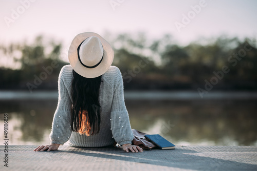 Photos Unrecognizable young woman with hat enjoying nature on the bank of a river
