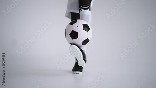 keepie uppie by football ball, closeup of player feet kicking and holding ball, technical skill photo