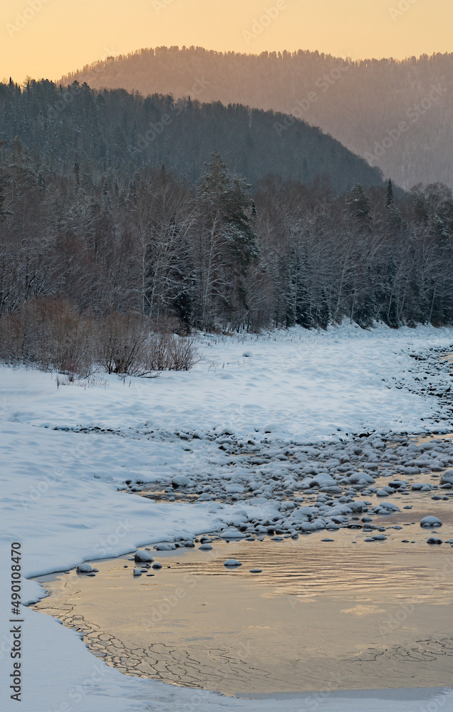 Russia. The South of Western Siberia, the Altai Mountains. A cloudless frosty dawn on the not frozen snow-covered Biya River near the village of Kebezen. Russia. The South of Western Siberia, the Altai Mountains. A cloudless frosty dawn on the not frozen snow-covered Biya River near the village of Kebezen.