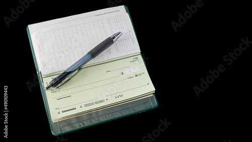 Open checkbook and pen on a black background.