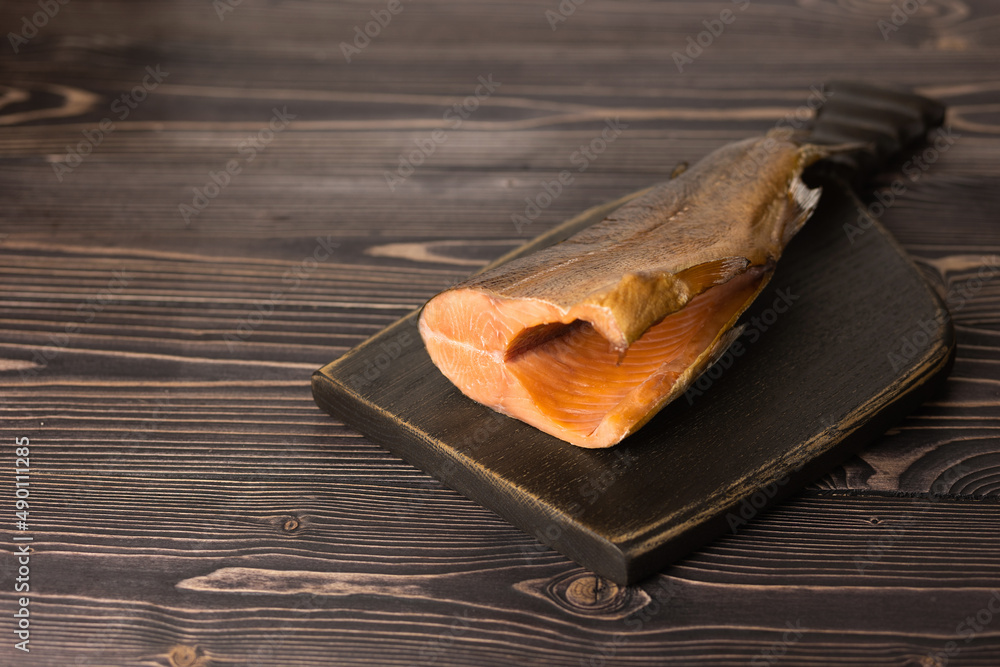 smoked trout on a wooden, dark board with a place to copy. Selective focus.
