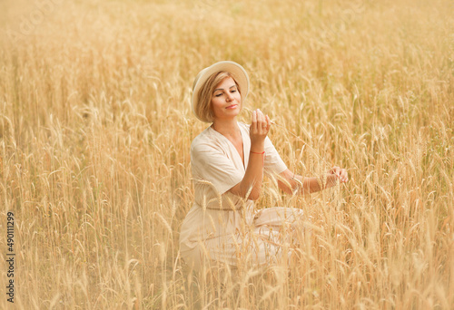 A girl in a wheat field looks at wheat grains.