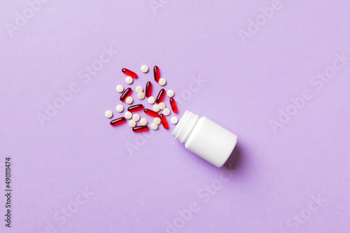 Multicolored pills and capsules in plastic bottle on Colored background, copy space. Many different various medicine tablets and pills, vitamin and nutritional supplements concept