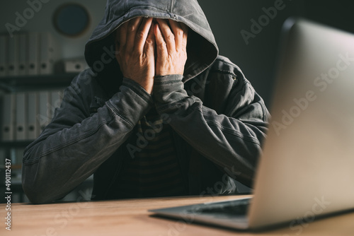 Canvas Print Regretful computer hacker covering face with hands in front of laptop