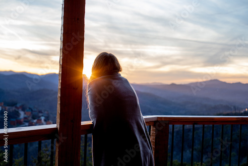 A young woman looks out over the mountains from her cabin