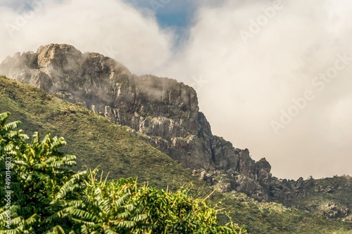 Monte constituído de pedras e iluminado pelo sol da manhã, com neblina e muita mata verde em volta, visto de quintal de sítio na região de Igarapé, Minas Gerais photo