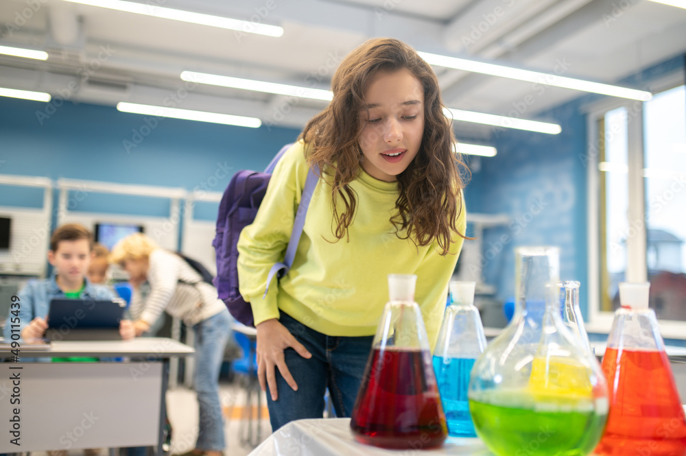 Girl leaning over laboratory flasks in classroom Girl leaning over laboratory flasks in classroom