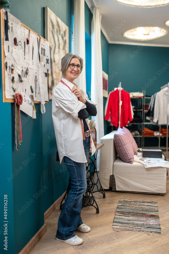Woman standing sideways to camera in cozy sewing workshop