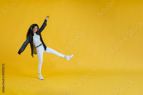 African American woman, with headphones listening to music and dancing. Yellow background