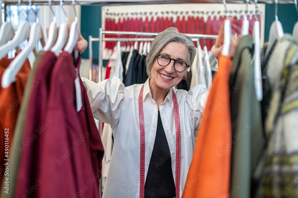 Woman touching clothes on hanger smiling at camera Woman touching clothes on hanger smiling at camera
