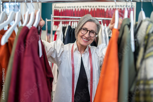 Woman touching clothes on hanger smiling at camera