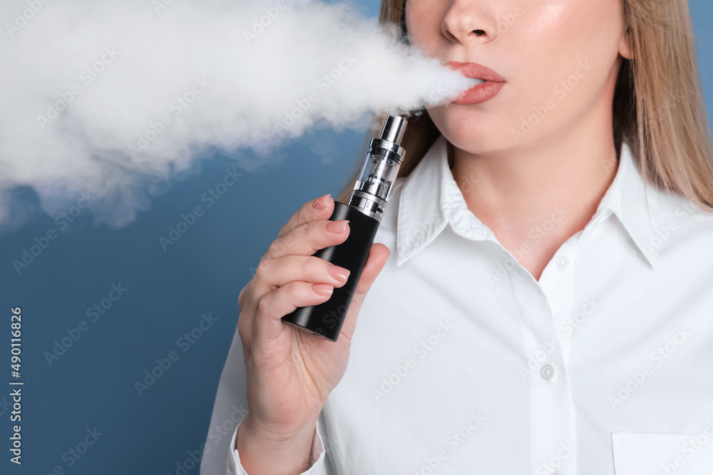 Young woman using electronic cigarette on light blue background, closeup Young woman using electronic cigarette on light blue background, closeup