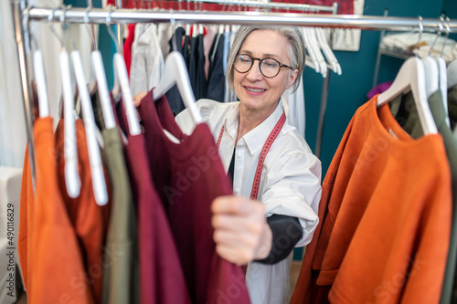 Woman standing near clothes rack touching dress