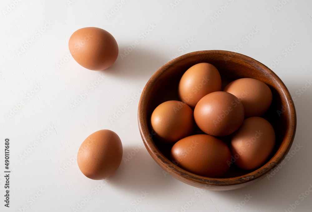 Top view brown eggs in wooden bowl on white table. Top view brown eggs in wooden bowl on white table.