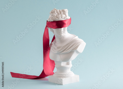 Plaster head with eyes covered red satin ribbon on blue background. photo