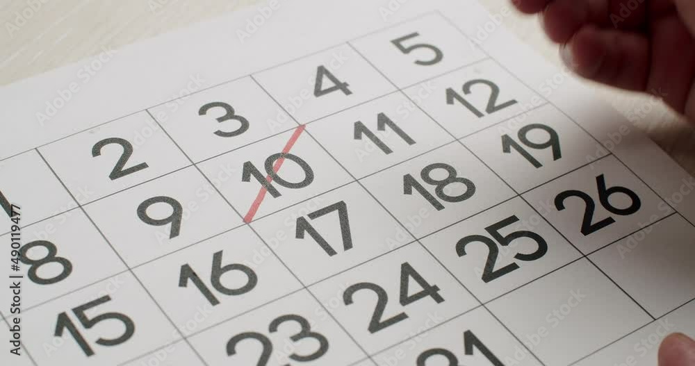 Calendar 10th Date of the Month Crossed Out. Hand crosses out of the Ten day on the paper calendar using a Red Pen. Very important date on the calendar. Signing a day on a calendar. Calendar 10th Date of the Month Crossed Out. Hand crosses out of the Ten day on the paper calendar using a Red Pen. Very important date on the calendar. Signing a day on a calendar.