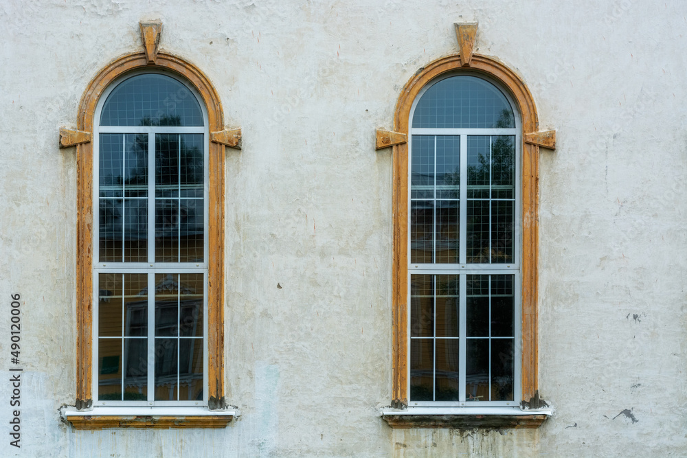 Two old arched windows on the background of an old gray wall. From the Windows of the world series.