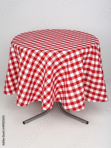 red checkered tablecloth spread out on a round table on a white background