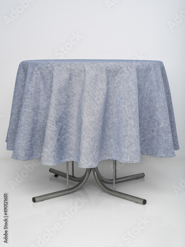 blue tablecloth spread out on a round table on a white background
