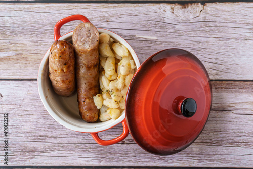 Sausages with white beans, in catalan butifarra con mongetes, typical dish from catalonia, spain. Red pot photo