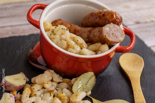 Sausages with white beans, in catalan butifarra with mongetes, typical dish from catalonia, spain. slate plate and wooden spoon. photo