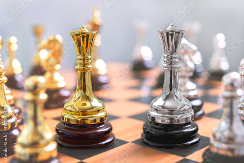 Focus on two Queens next to each other among other chess pieces. The concept of confrontation, the struggle of leaders, the strategy of winning in a chess game.