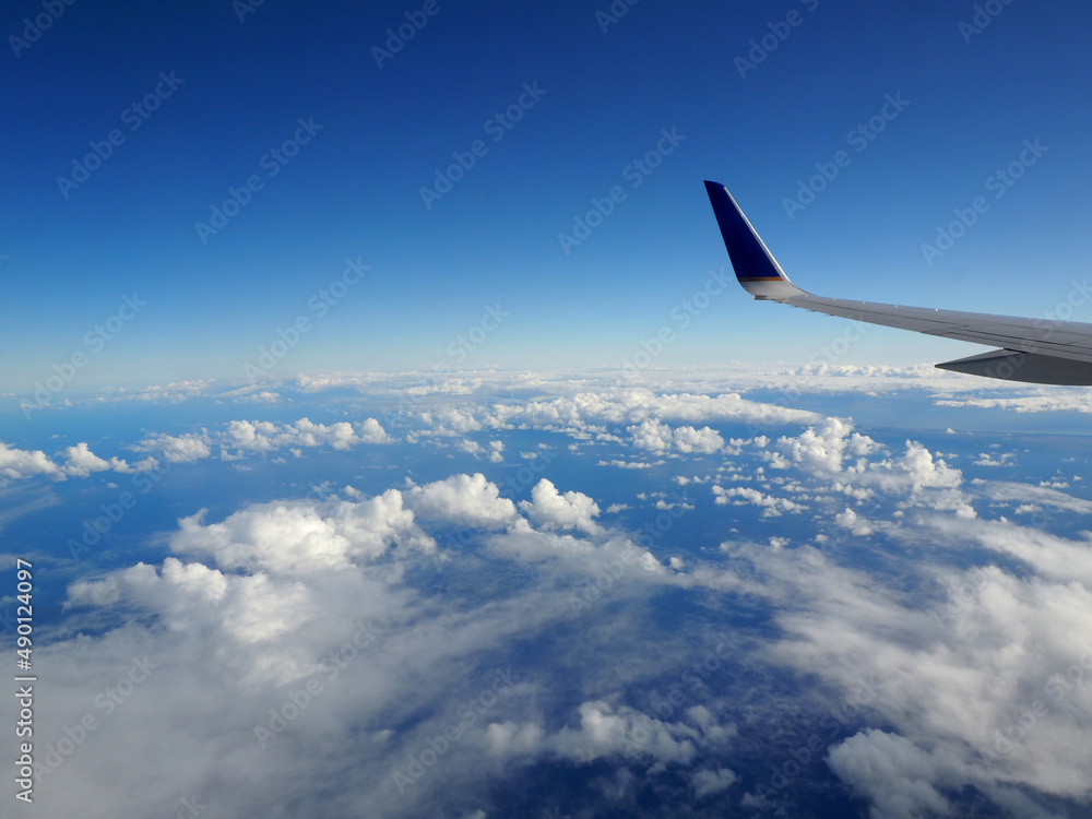 Aerial high in the sky shot from above the clouds with the wing of a commercial jet plane Aerial high in the sky shot from above the clouds with the wing of a commercial jet plane