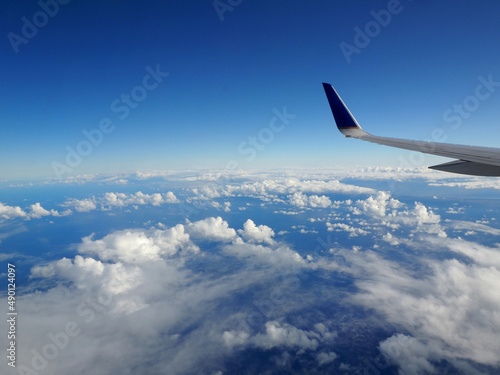 Aerial high in the sky shot from above the clouds with the wing of a commercial jet plane