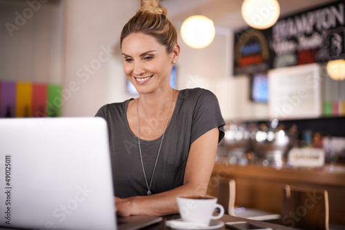 Shes a woman in touch with technology. A beautiful woman using her laptop in a coffee shop.
